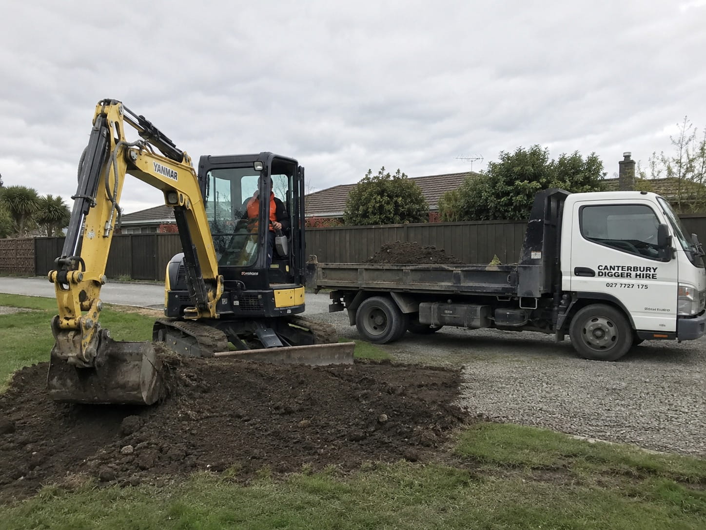 Excavator cutting back a slope to prepare a base for a retaining wall in Christchurch