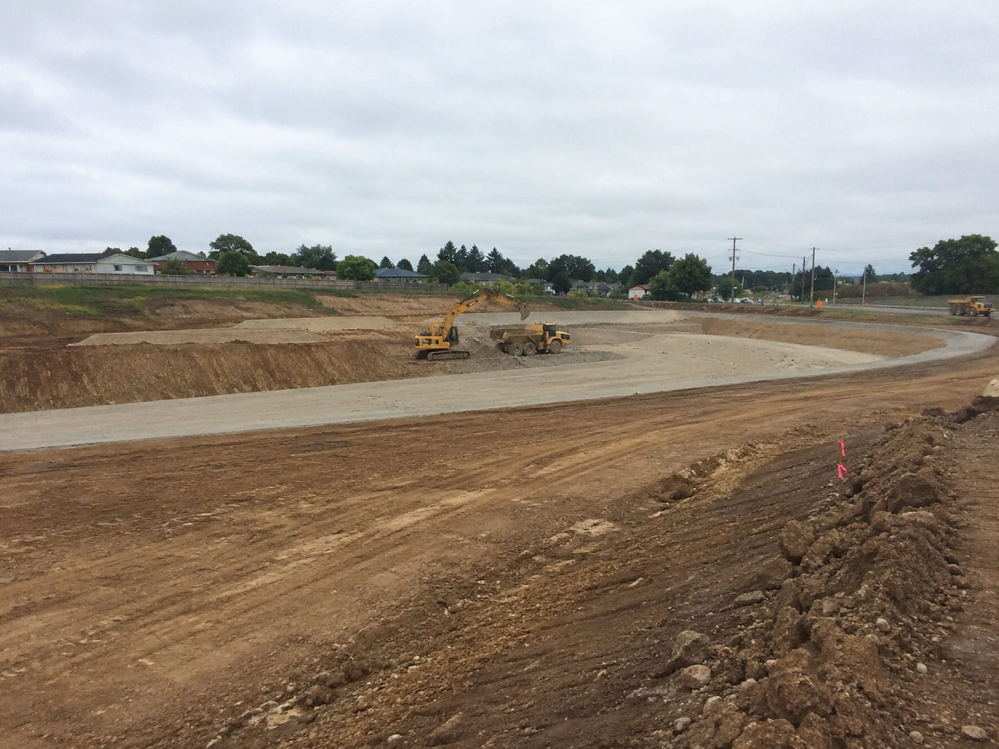 Excavator loading an articulated dump truck during bulk earthworks on a Christchurch subdivision