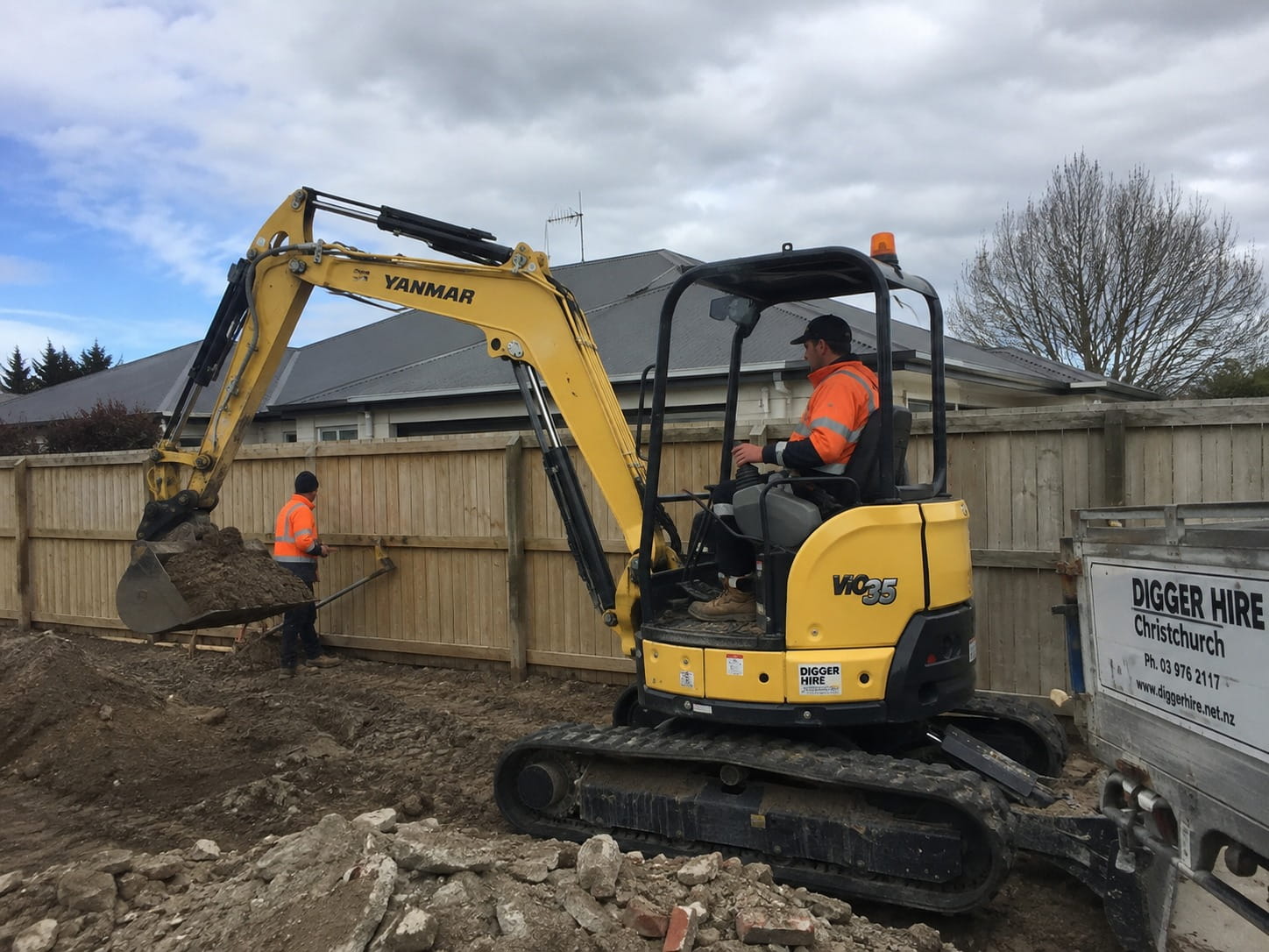Mid-sized excavator digging out a level base for an in-ground swimming pool in Christchurch