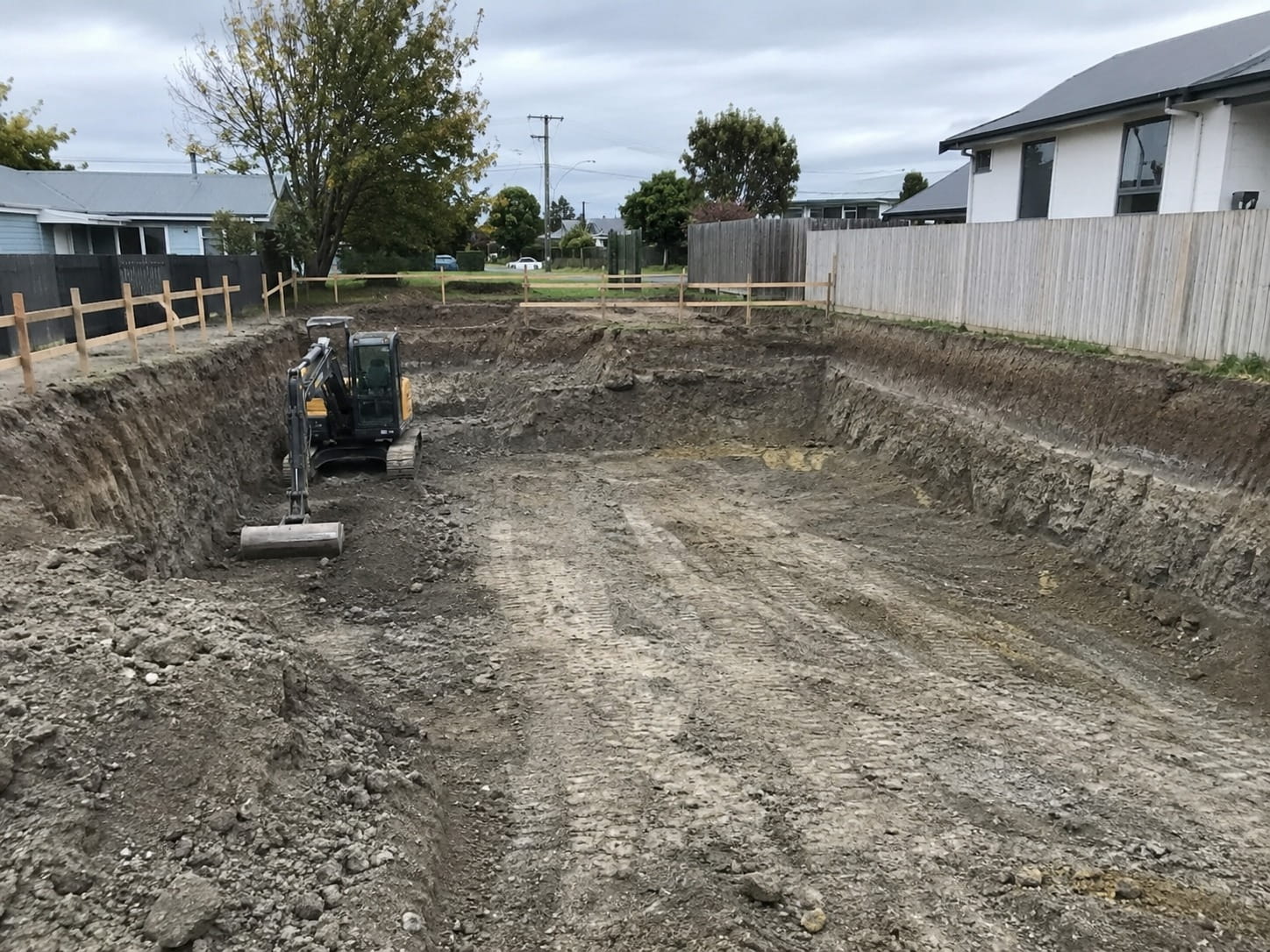 Digger working in a deep excavation for a basement and foundation in Christchurch